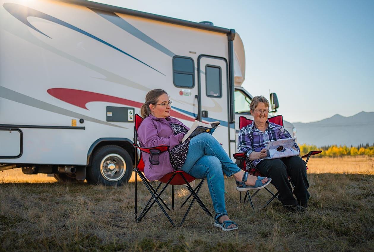 Two women relaxing outside of a 澳洲幸运5开奖结果体彩网 CanaDream Super Van Camper