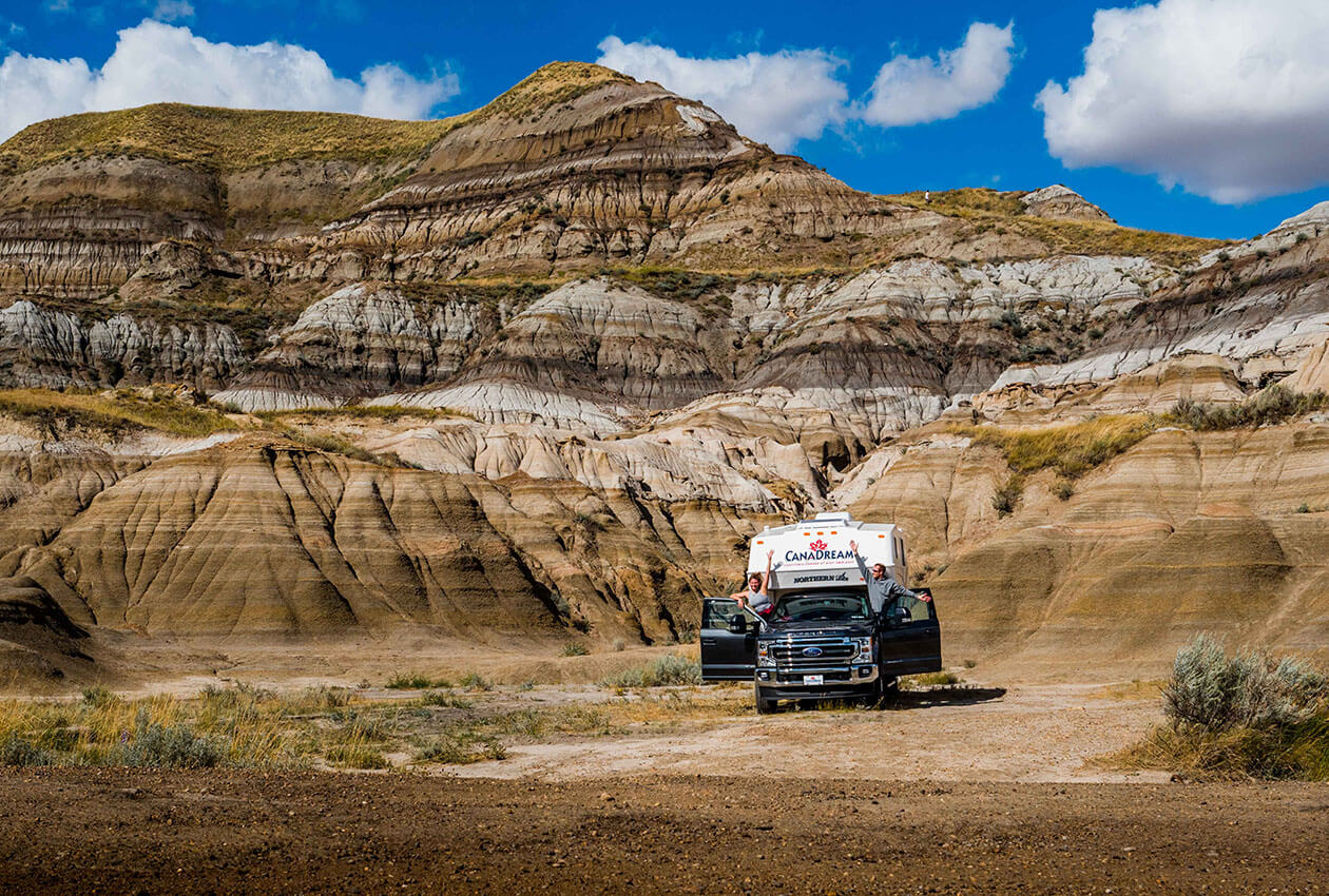 Couple in CanaDream RV truck and camper with hoodoos behind Drumheller Alberta